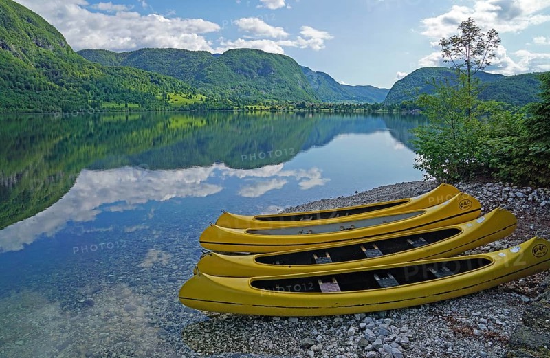 Yellow kayaks on the shore, mountain range reflected in Lake Bohinj, Triglav National Park, Julian Alps, Gorenjska region or Upper Carniola, Slovenia, Europe