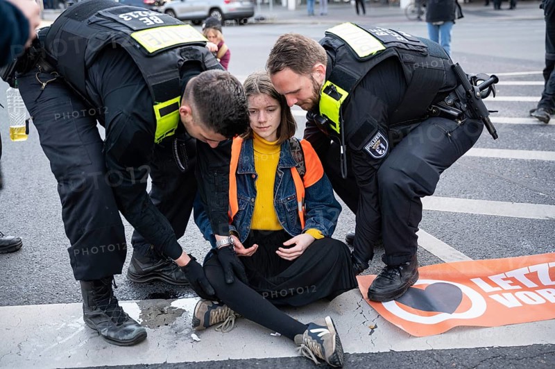 28.04.2023, Berlin, Germany, Europe, Climate demonstrators of the so-called Last Generation stick to the carriageway of a main road at Ernst-Reuter-Platz in Berlin-Charlottenburg and cause severe traffic obstructions while officers of the Berlin police carry one of the activists off the road. The activists' main demands are an affordable 9-euro ticket for everyone and a general speed limit of 100 km/h on German motorways. The group is also calling on the German government to take more drastic measures to reduce greenhouse gas emissions and to phase out the use of all fossil fuels by 2030, as well as calling for a social council, Europe