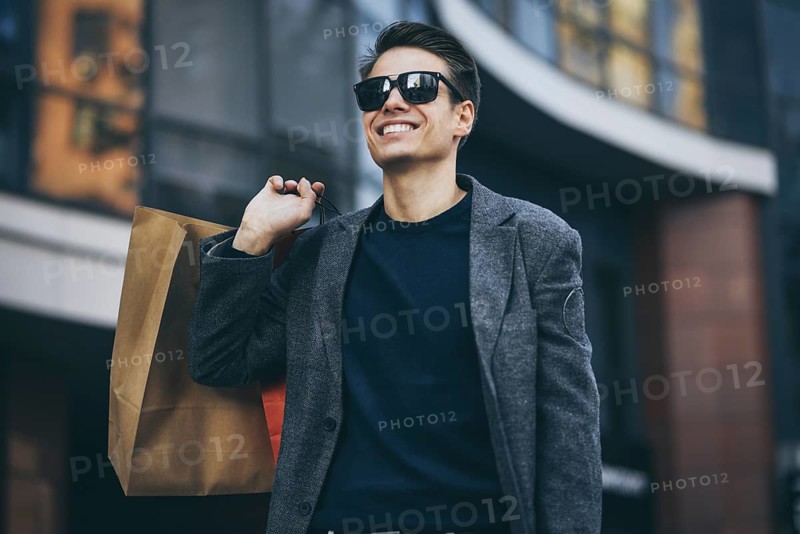 Serious cool guy with sunglasses and paper bags walking at street