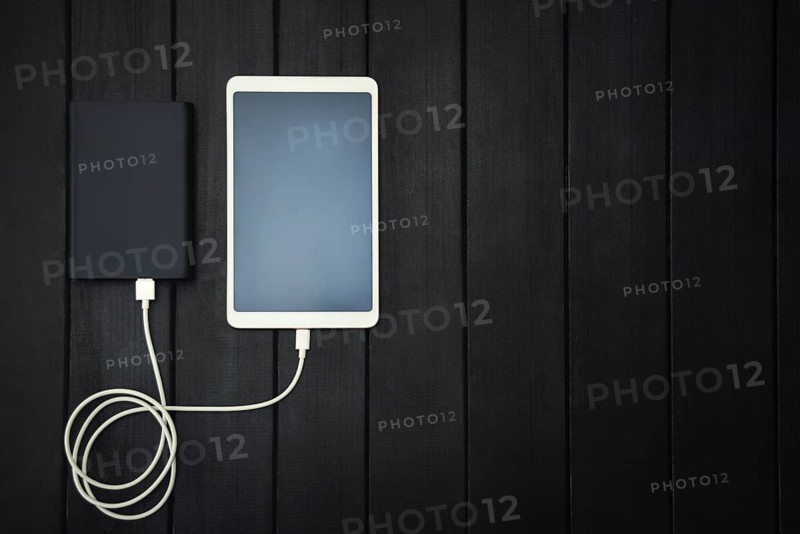 Power bank loads tablet PC, smartphone, isolated on wooden background. charging concept. free copyspace