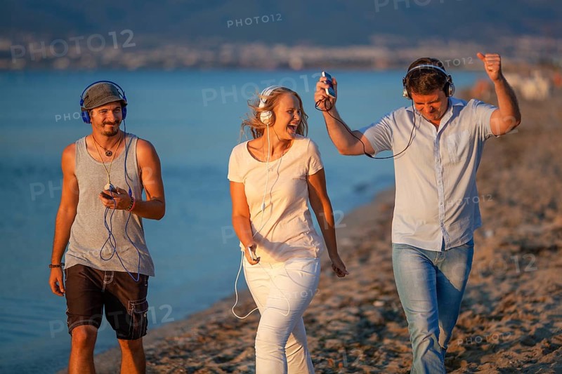 Excited friends outdoor. Young people relaxing and having fun listening to music in headphones