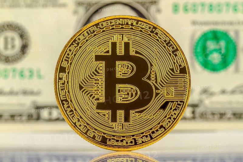 Bitcoin with dollar bill in the background
