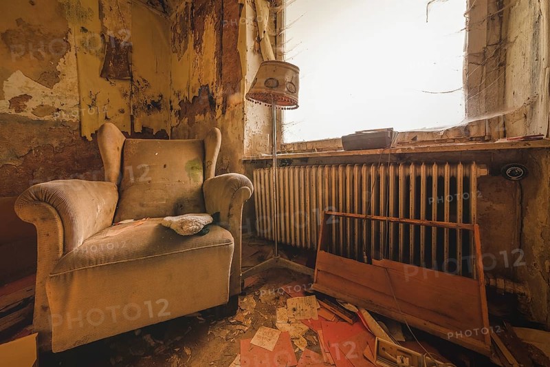An outdated room with armchair and lamp next to a neglected heating system, Lost Place, Urologist's Villa Dr Anna L., Bad Wildungen, Hesse, Germany, Europe