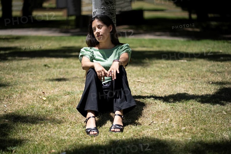 Latin woman sitting in a park with a thoughtful expression