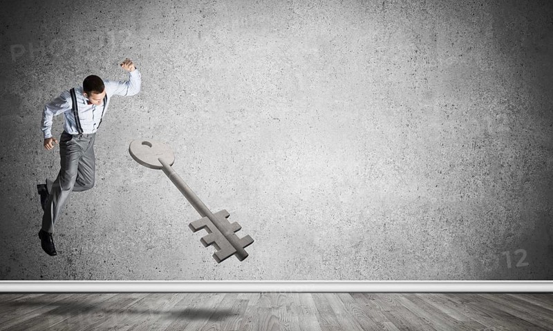 Determined businessman in empty interior breaking with fist stone key figure