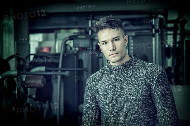 Handsome white asian young man wearing grey sweater, standing indoor in dark place