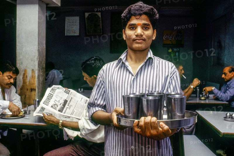 Waiter serving drinking water steel glasses, Udipi restaurant, Mumbai, Maharashtra, India, Asia