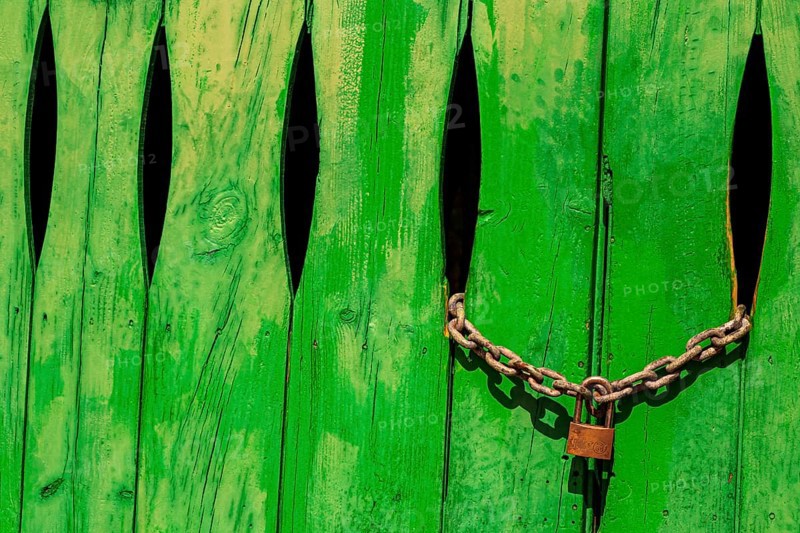 Green door in the stone wall with lock locked in Cala Figuera Mallorca Spain