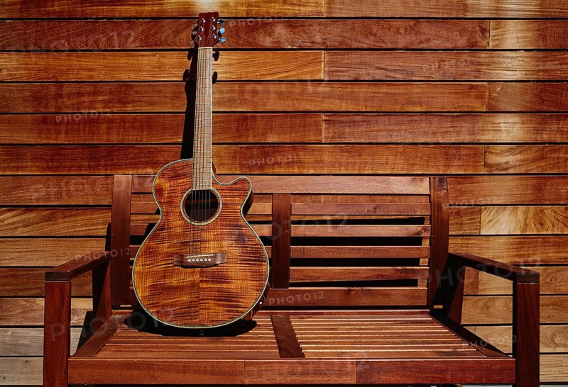 Acoustic brown guitar in a wooden stripes wooden wall monochromatic