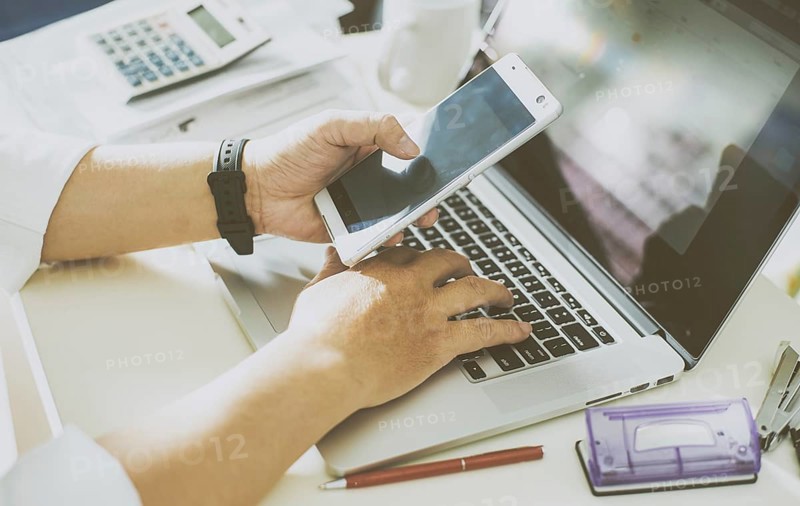 Businessman hand using smart phone and keying the data to laptop, mobile payments online shopping.Seleted focus