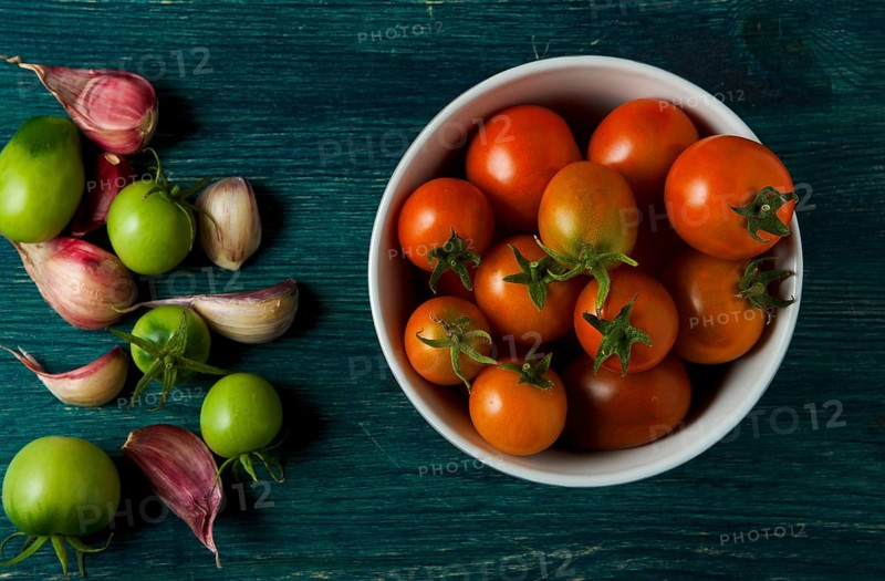 Tomatoes on the background. Tomatoes, garlic on a wooden surface. View from above. Fresh vegetables. copy space