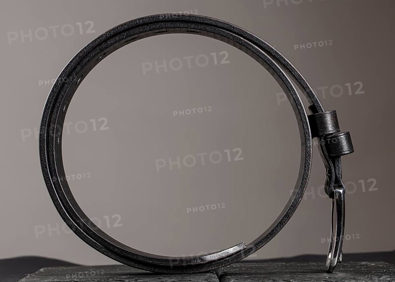 Leather belt twisted into a circle on a grey background