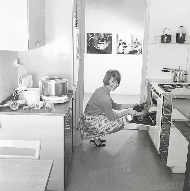 In the kitchen in the 1960s. A young woman in the kitchen taking out the ready baked breads from the oven. The food procossor in it's typical 1960s look is seen on the kitchen counter. Sweden 1963. ref BV79-9