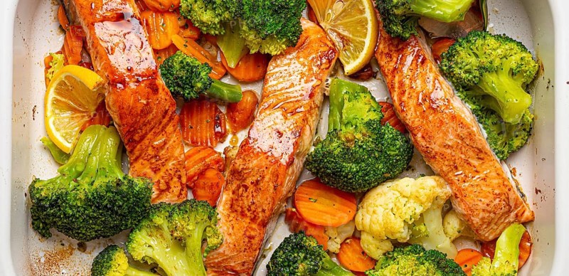 Top view close up of healthy baked fish salmon steaks, broccoli, cauliflower, carrot in casserole dish. Cooking a delicious low carb dinner, healthy nutrition concept, food photography