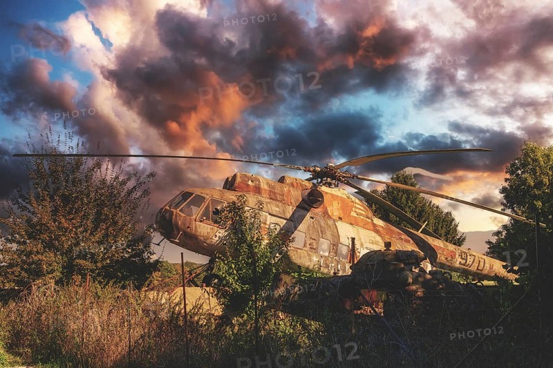 An abandoned, rusty helicopter stands overgrown in nature under a dramatic, cloudy sky at sunset, Mil Mi8 970, Babbenhausen, Bad Oeynhausen, North Rhine-Westphalia, Germany, Europe
