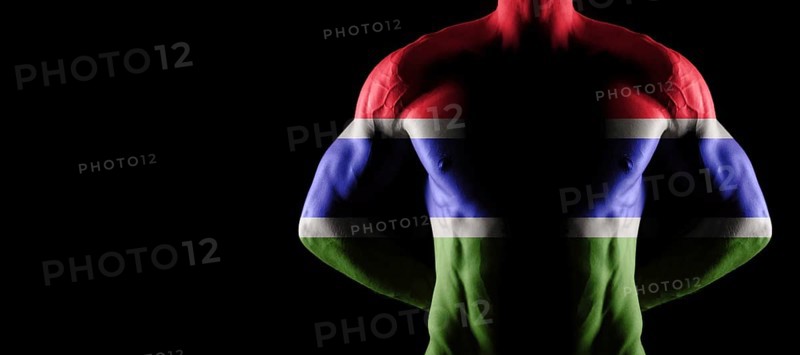 Gambia flag on muscled male torso with abs, black background