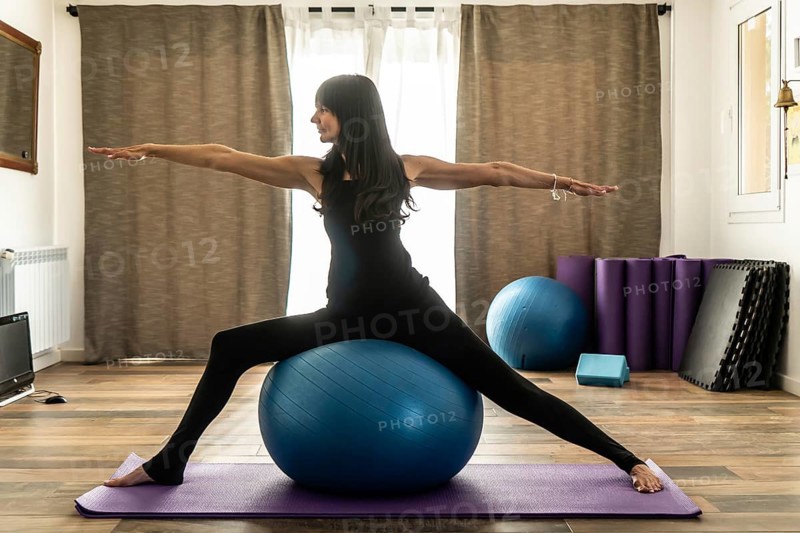A woman doing yoga with fitness ball in studio