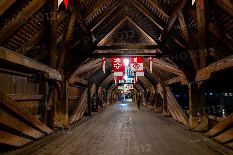 Inside the Old Historical Covered Wood Bridge Holzbrücke with Flags over River Aare at Night in Olten, Canton Solothurn, Switzerland, Europe