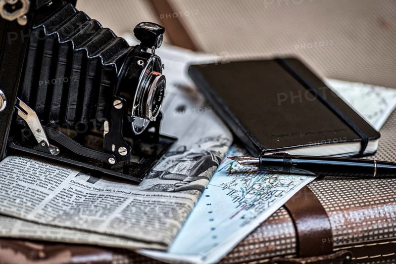 Still life with an old camera, pen, glasses and a road map in vintage style. Memories from travelling with an old camera, pen, glasses and a road map