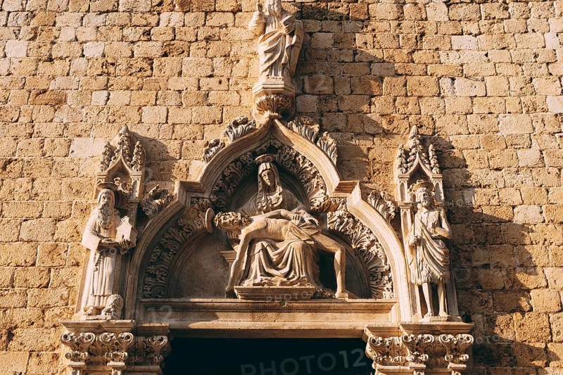 Facade of the Franciscan monastery with high relief depicting holy images in the old town of Dubrovnik, Croatia.