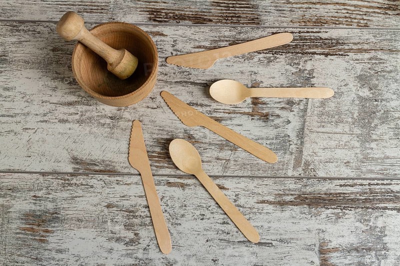 Wooden mortar with a pusher and other tools. Knives and spoons. Top view flat lay