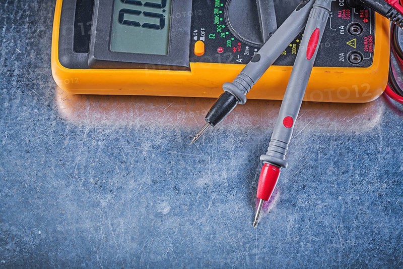 Digital electric tester test leads on metallic background