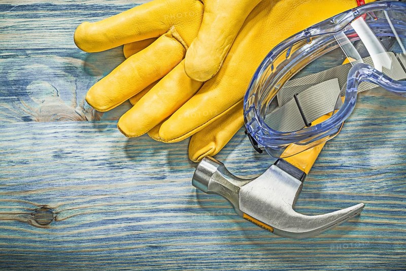 Protective glasses leather gloves claw hammer on wooden board construction concept
