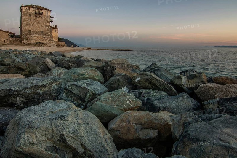 View over the sea into the sunset. Landscape taken with the historical landmark of the Byzantine tower of Prosphorion on the coast of Ouranoupoli, Thessaloniki, Central Macedonia, Greece, Europe