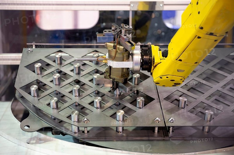 Yellow robotic arm arranges metal elements after being produced. Automatic industrial machinery equipment