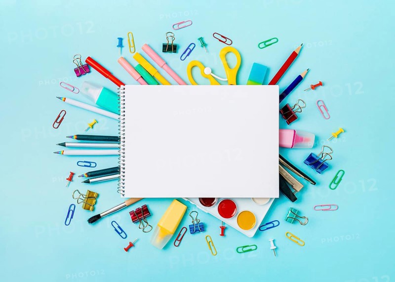 Notebook with stationary objects on blue background. Empty white paper sheet of notepad or sketchbook over shool supplies, isolated on blue. Copy space for text or design. Top view, flat lay