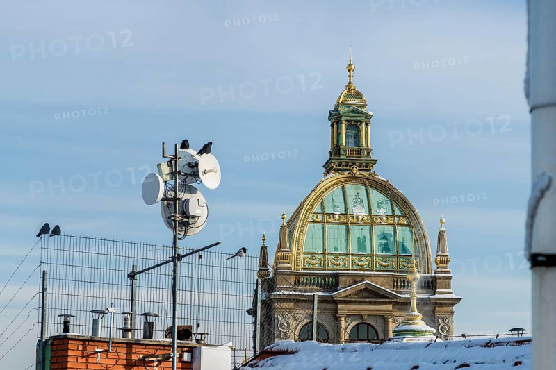 View of a historic dome with antennae and birds in a cityscape in winter, Czech National Museum