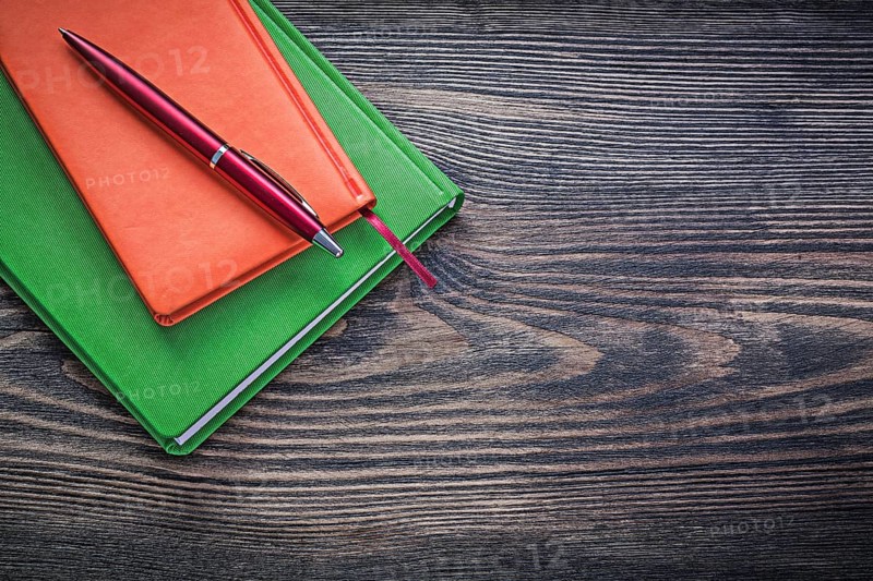 Closed diary books ballpoint pen on vintage wood board office concept