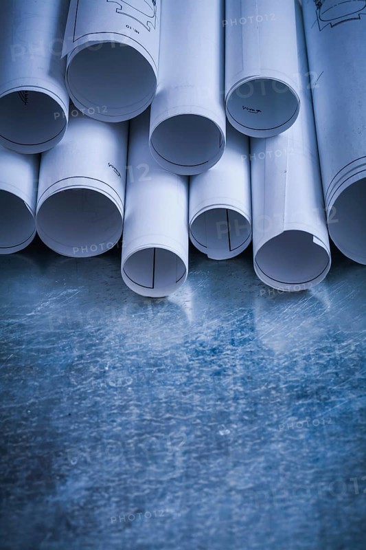 Pile of rolled engineering drawings on scratched silver-metal background building and architecture concept