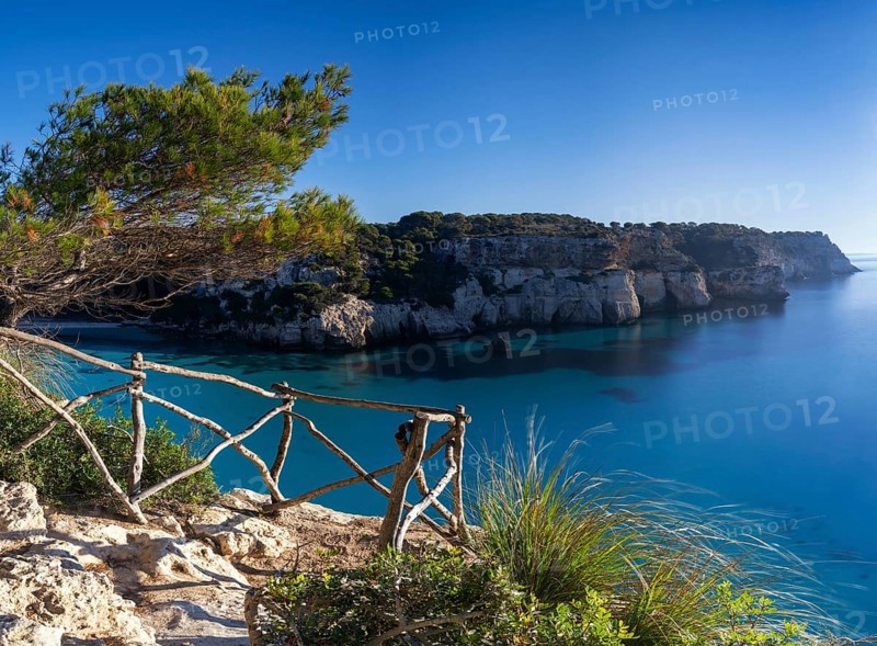 A landscape view of the idyllic Cala Macarella in southern Menorca with a hiking trail in the foreground
