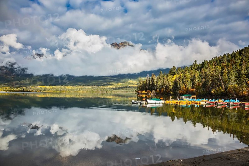 Pyramid Mountain reflected in Pyramid Lake. Wooden boat dock with moored pleasure boats and benches