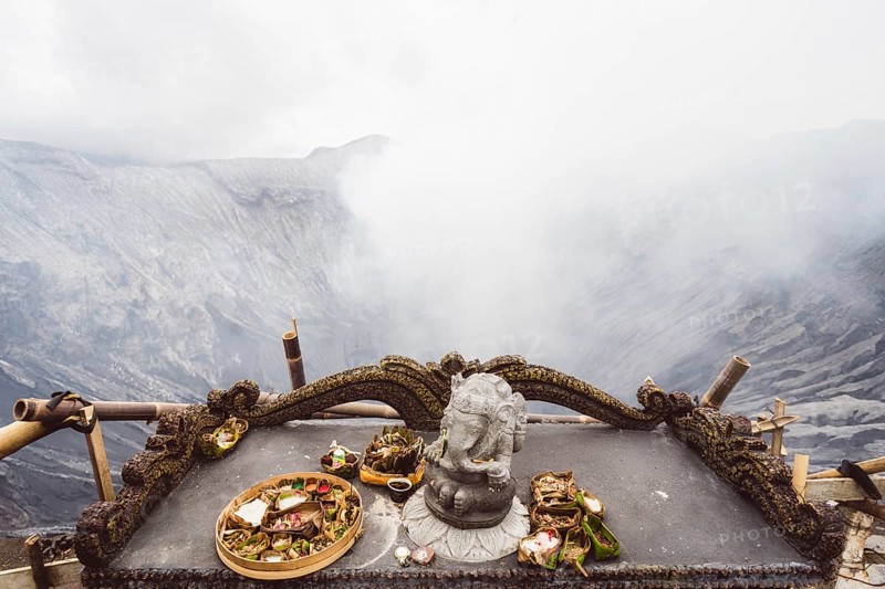 Traditional offerings and a statue on an altar with a misty volcano background, Bromo volcano, Sri Lanka, Asia