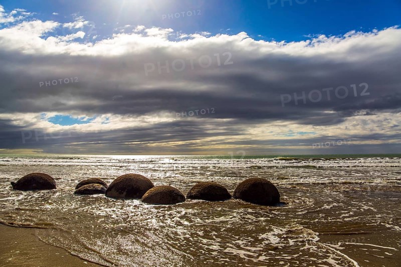 Moeraki boulders. Ocean tide begins. Group of large round boulders on the coast of the South Island of New Zealand. Sunset. The concept of active, ecological, exotic and phototourism