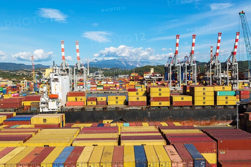 High angle view of stacked rectangular metal box shipping containers on dock waiting to be loaded onto MSC Renaissance III cargo vessel in La Spezia cargo Port, Italy, Europe