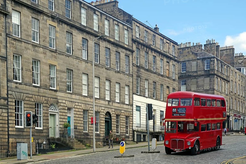 Red double-decker bus in historic old town with classic buildings and blue sky, Capital City, Edinburgh, Scotland, United Kingdom, Europe