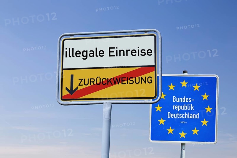 (Photomontage) Town exit sign with the inscription ILLEGAL ENTRY / REFUSAL in front of a border sign of the Federal Republic of Germany