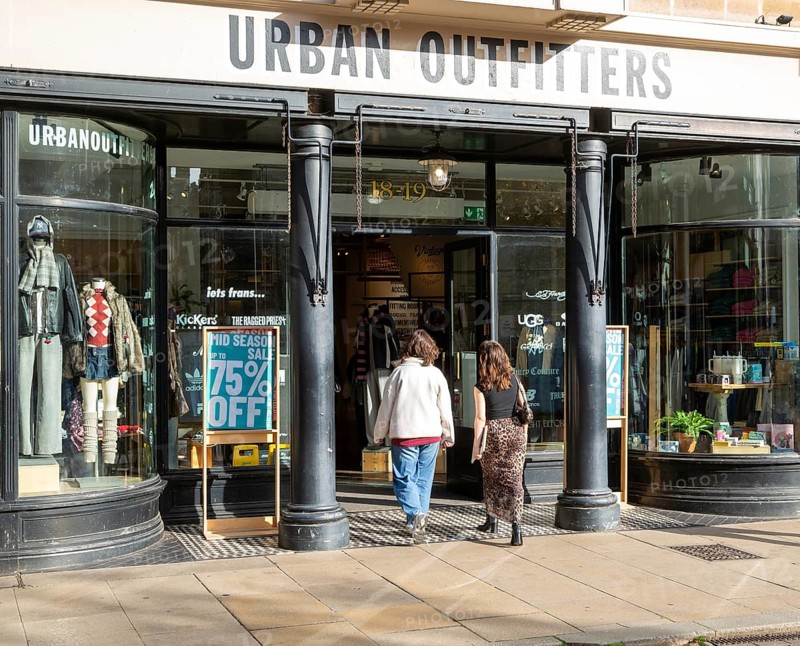 Urban Outfitters clothes shop store in city centre, Cambridge, Cambridgeshire, England, UK two women entering door