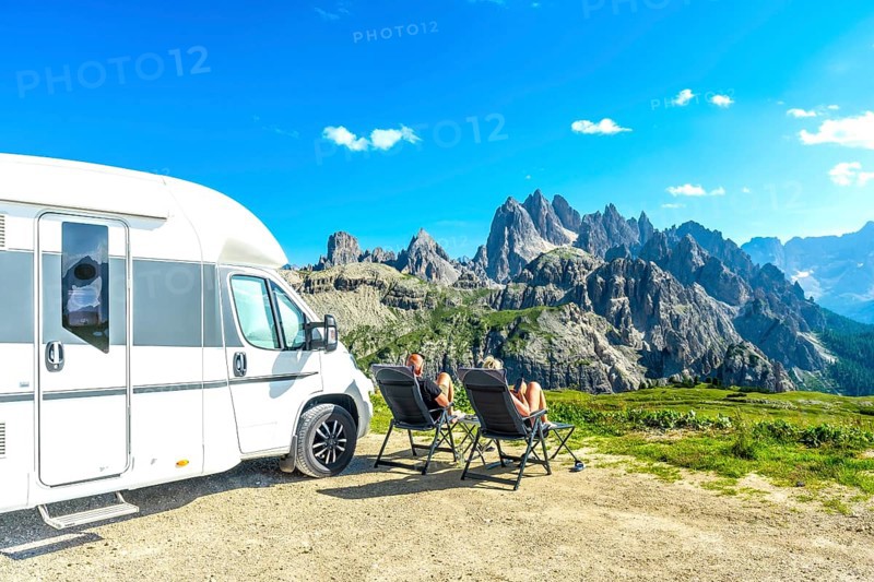 Family relaxing in camping chairs, enjoying breathtaking view of tre cime di lavaredo, dolomites, italy, during summer vacation with their camper van