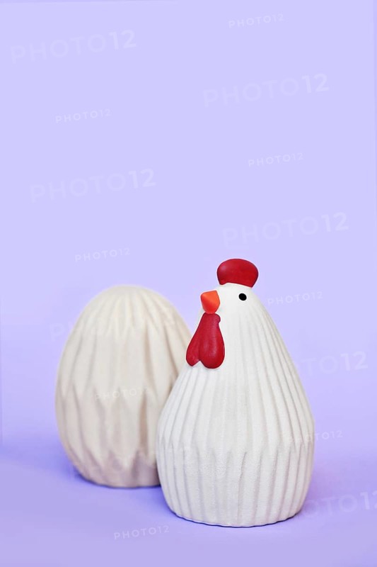 Ceramic Easter chicken and egg decoration objects on purple background with copy space