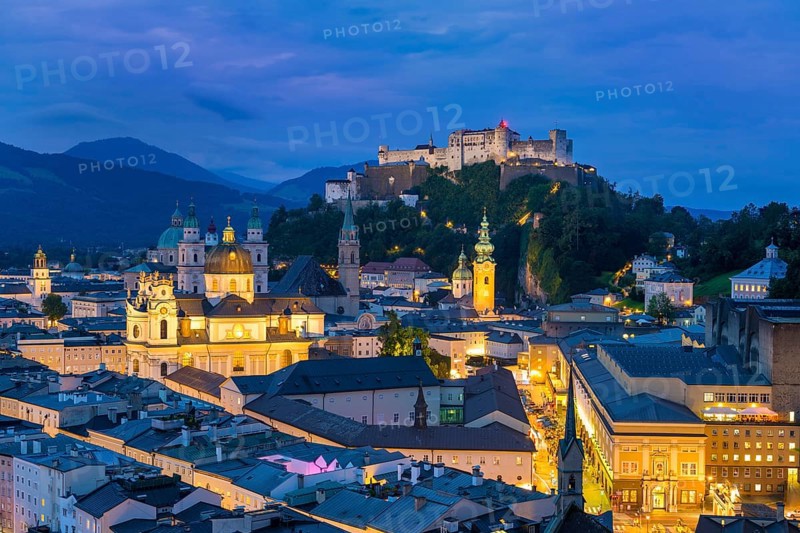 The city of Salzburg glows at dusk, dominated by the Hohensalzburg Fortress and the Alps, Salzburg, Salzburger Land, Austria, Europe