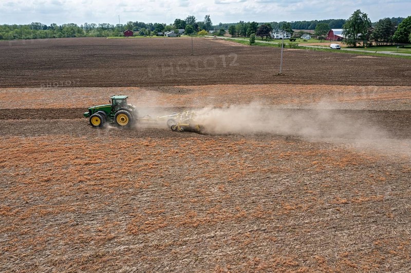 Hudson, Michigan, A cloud of dust blows behind the tractor as a farmer tills his field