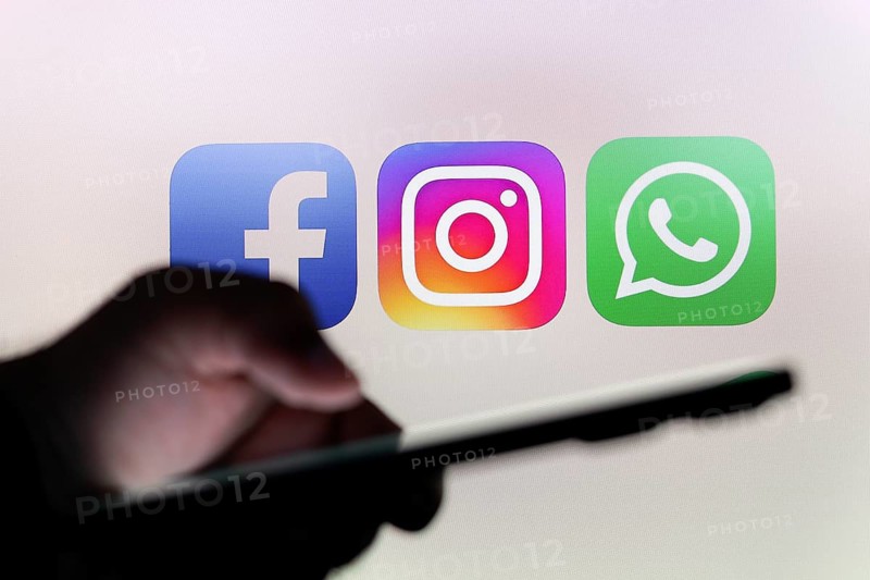 In this photo illustration the Facebook, Instagram and WhatsApp logo app seen in the background of a silhouette hand holding a smartphone
