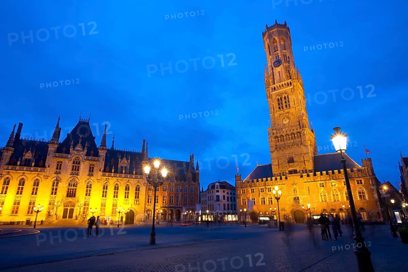 The provincial courthouse and belfry are illuminated at dusk in grote markt, the city center of Brugge, Belgium, Europe