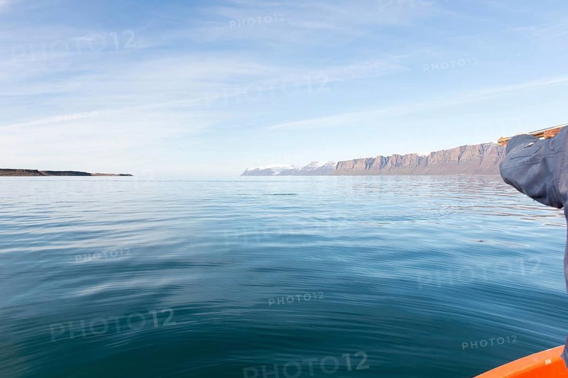 Greenlandic man hunting for seal in Greenland, pointing the gun towards the water, Greenland, North America