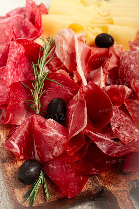 Assorted meat, appetizer, prosciutto, salami and ham, with maasdam cheese and olives, on a wooden board, breakfast, top view, close-up, no people