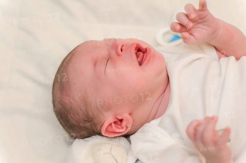 Newborn baby crying, close-up of baby lying in bed
